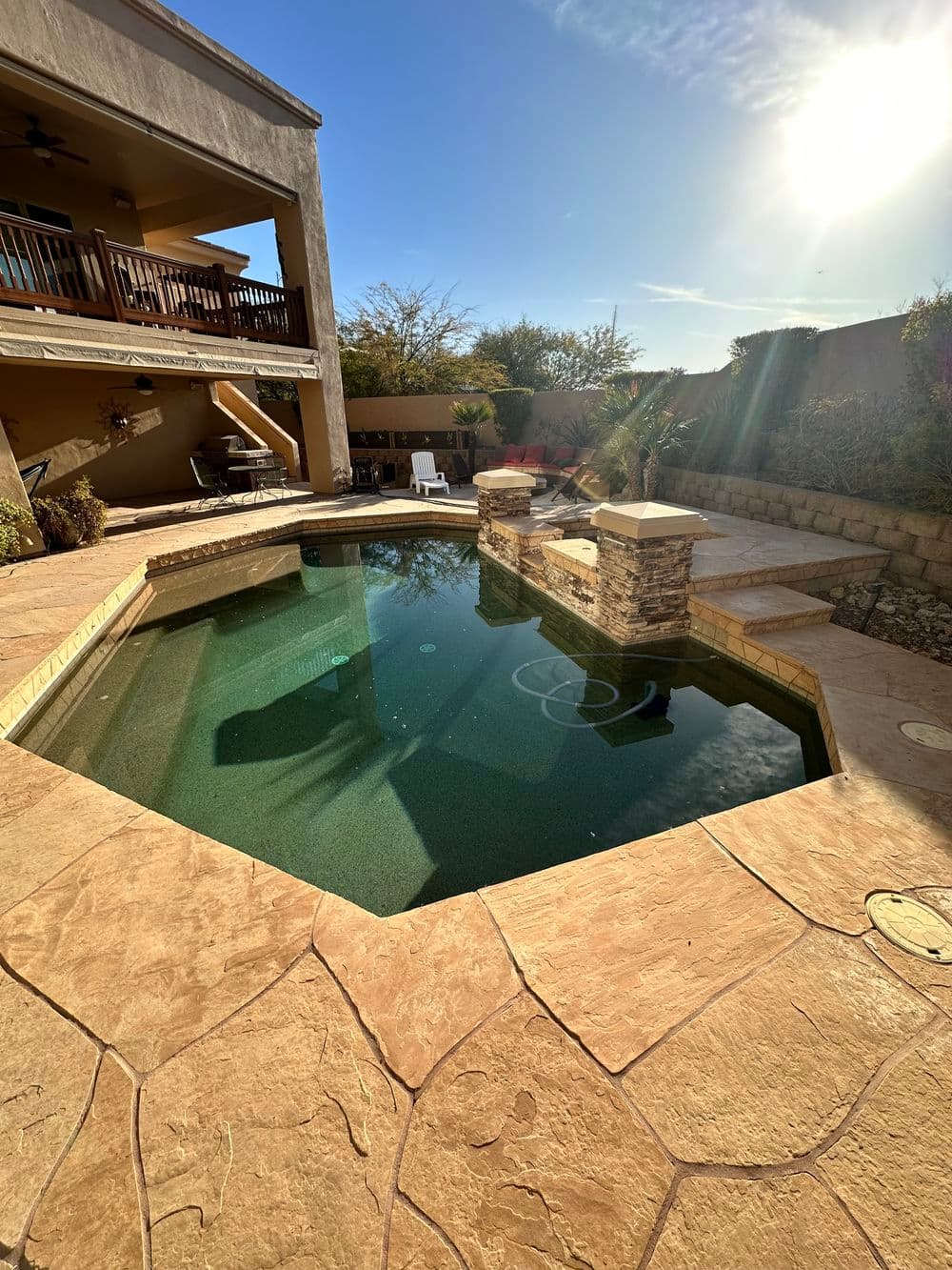 Modern backyard pool with stone accents and sunny sky, perfect for outdoor relaxation.
