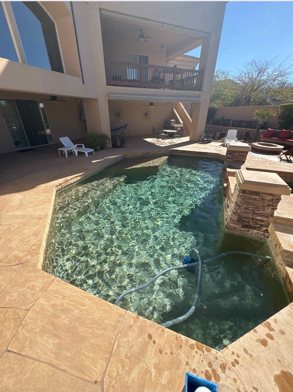 Modern backyard with a crystal-clear octagonal pool and patio furniture under a sunny sky.