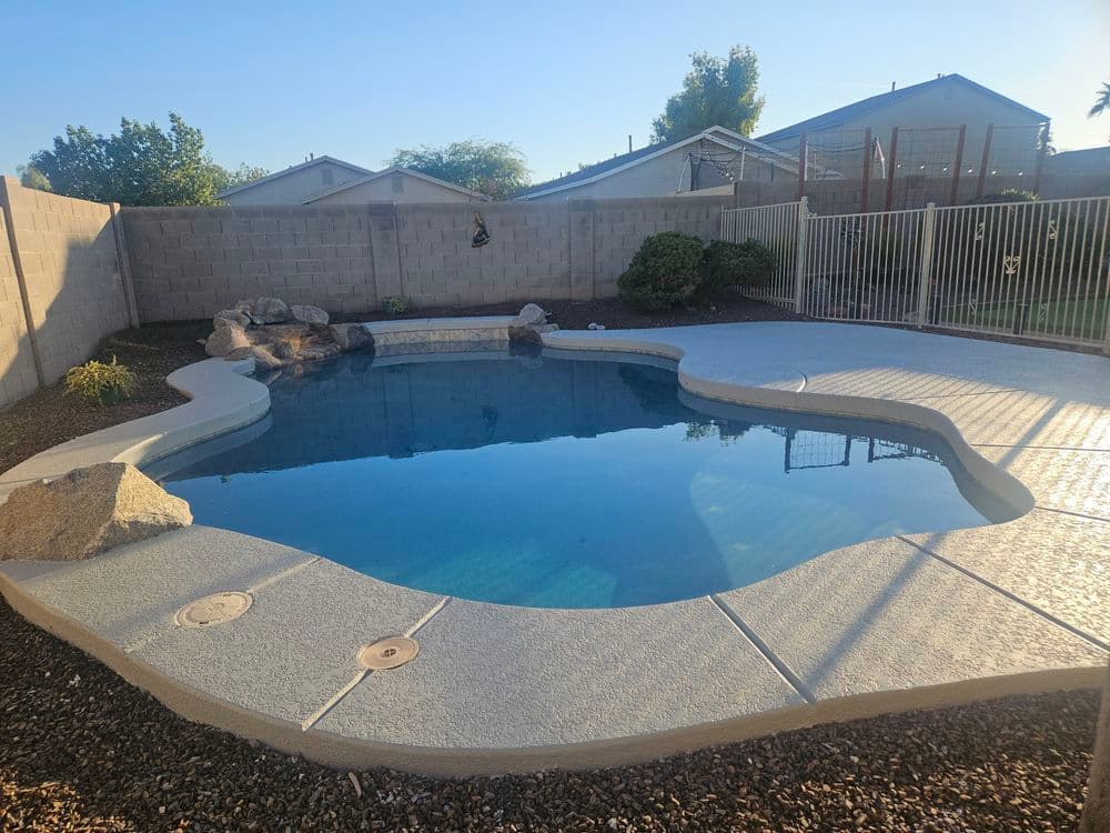 Sparkling pool with rock features and surrounding landscaping in a residential backyard.