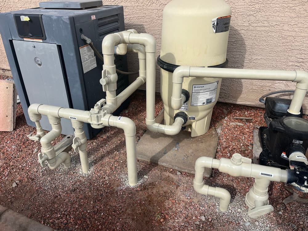 PVC plumbing system installation with pump and filter equipment in a residential setting.