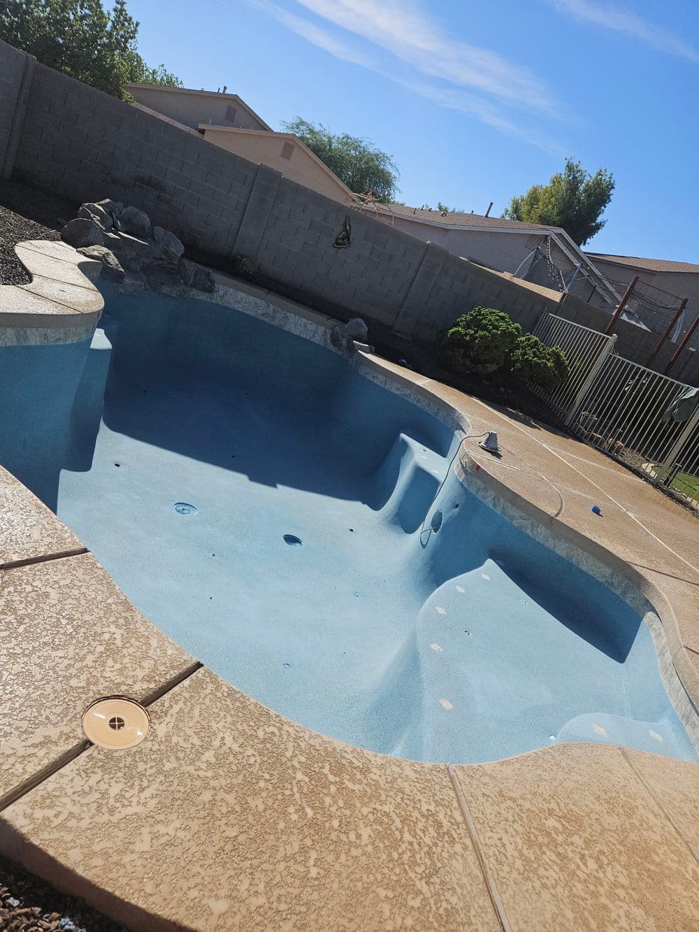 empty swimming pool in backyard with clear blue water and surrounding landscaping