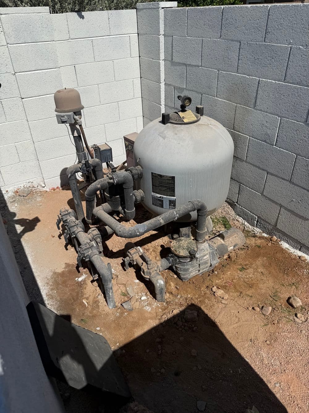 Industrial water pump system with pipes and pressure tank in a fenced area.